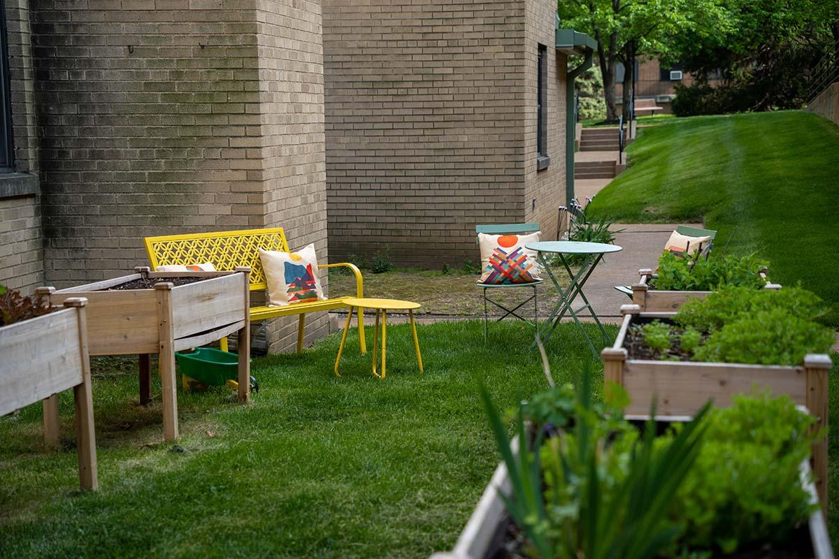 Brightly colored chairs sitting on a lawn outside a building with landscape boxes nearby.